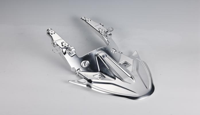 Shiny metal motorcycle part on gray background.