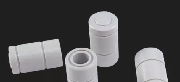 White cylindrical modular pipe connectors on black background.