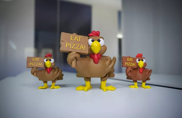 Toy chickens holding 'Eat Pizza' signs.