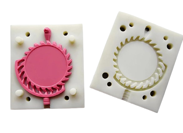 Two plastic gear molds, one pink, one white.