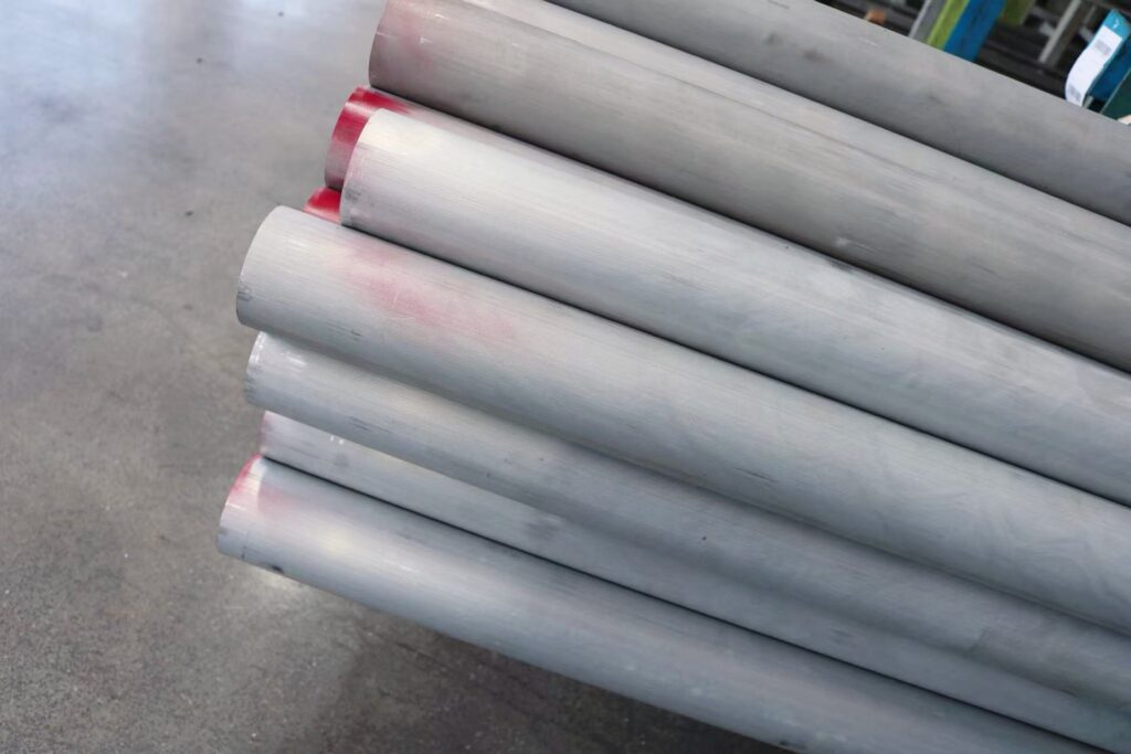 Stack of gray metal pipes on concrete floor.