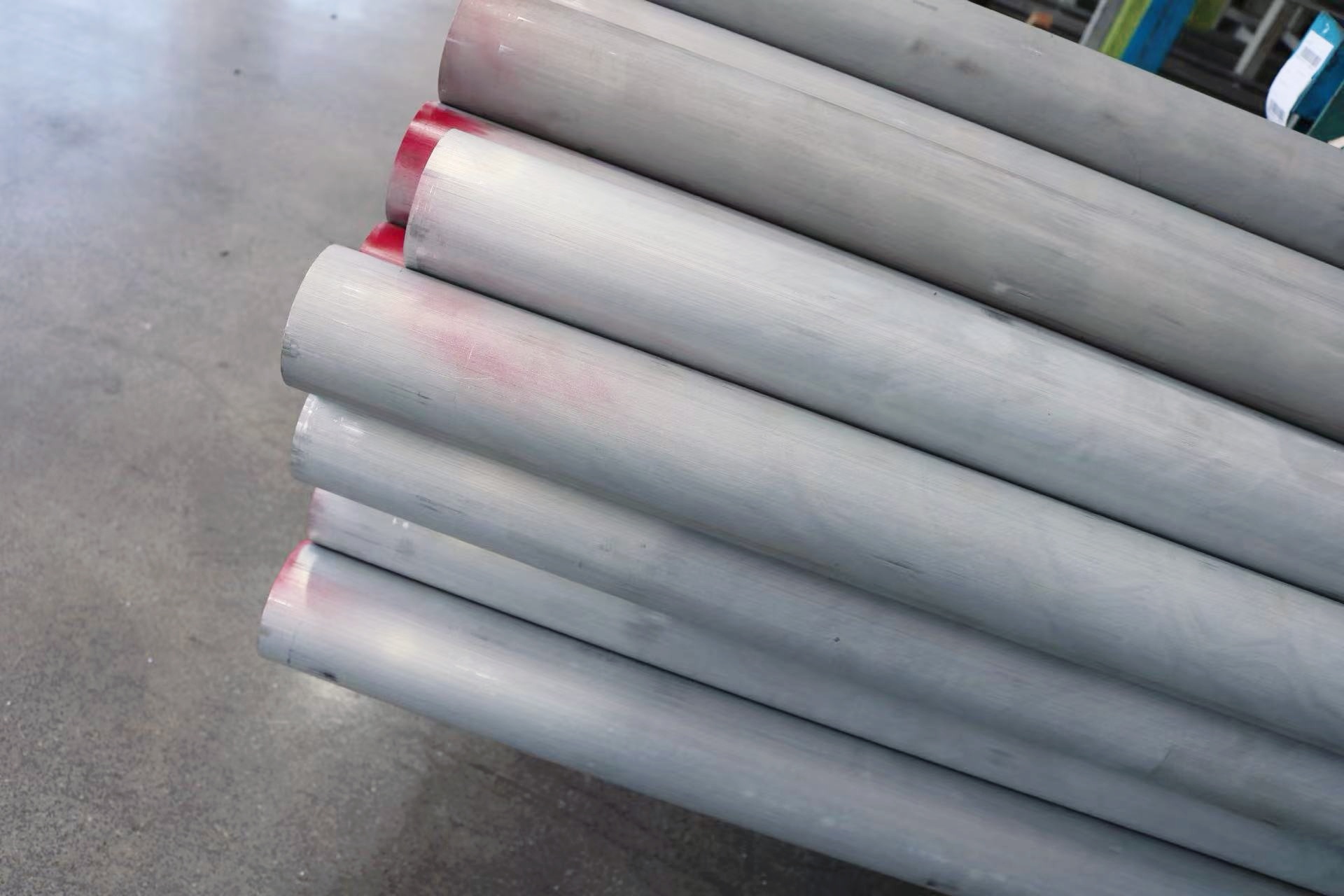 Stack of gray metal pipes on concrete floor.