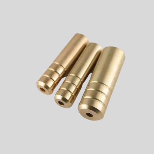 Three cylindrical brass parts on gray background